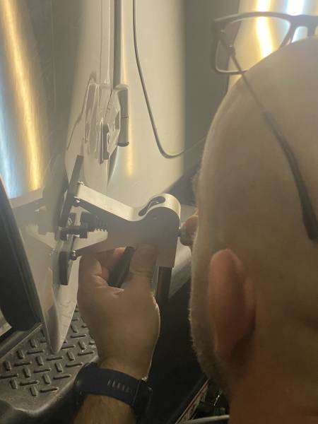 Intervention d’un débosselage sans peinture avec une pince à colle chaude sur portiére